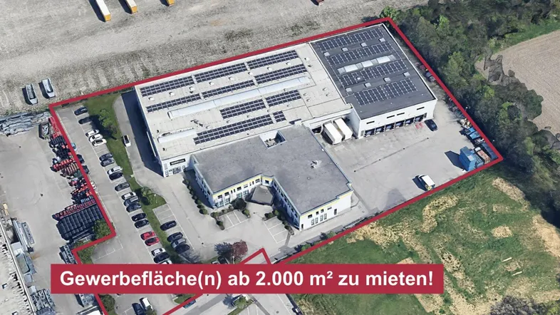 Luftaufnahme eines Gewerbekomplexes mit mehreren Gebäuden, Parkplätzen und Solaranlagen auf den Dächern.