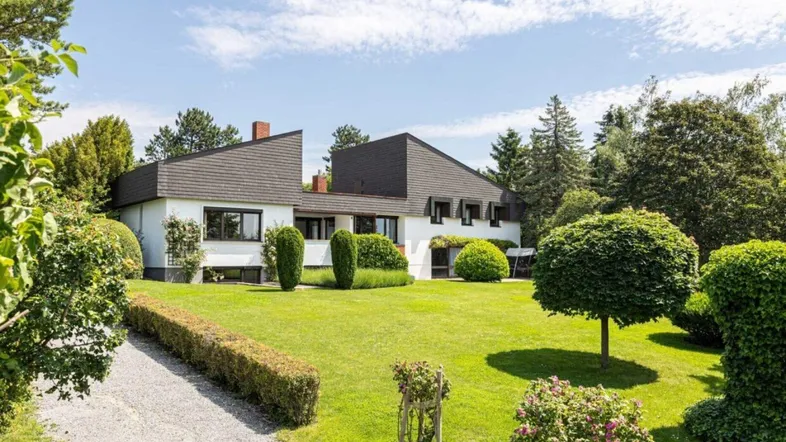 Großzügiges Anwesen mit modernem Haus und weitläufigem, gepflegtem Rasen unter blauem Himmel.