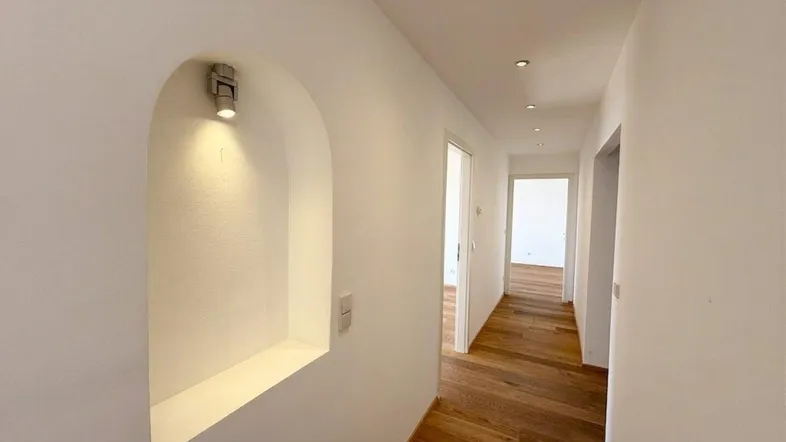 Heller Flur mit elegantem Holzparkett, Einbaustrahlern und einer beleuchteten Nische.