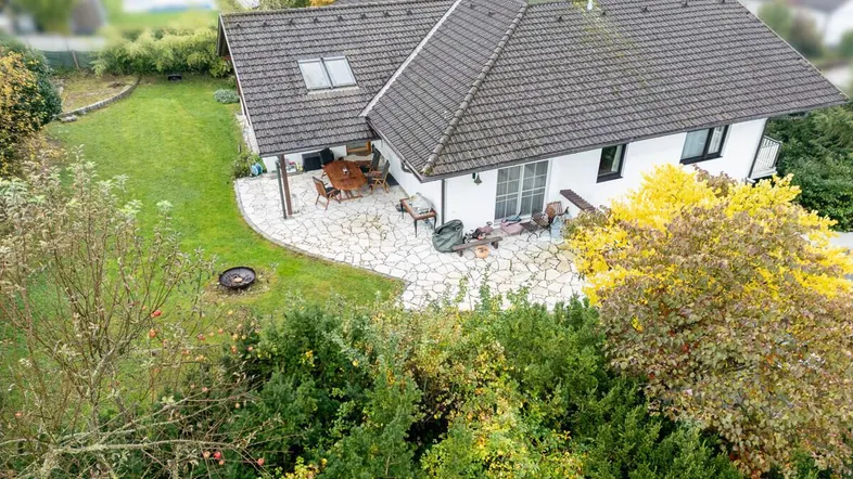 Luftaufnahme des Hauses von hinten, mit Terrasse und Gartenbereich, umgeben von viel Grün.