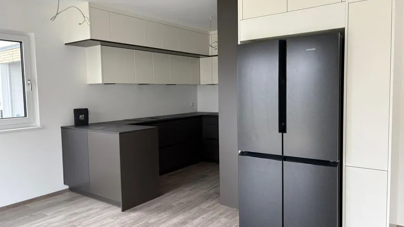 Moderne Einbauküche mit dunklen Arbeitsplatten und integriertem Kühlschrank in einem hellen Raum.