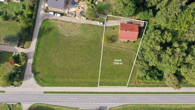 Luftaufnahme eines Grundstücks mit Einfamilienhaus, großem Garten und angrenzender Straße.