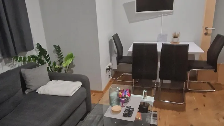 Geräumiger Wohn- und Essbereich mit modernem Sofa, Esstisch und Holzboden.
