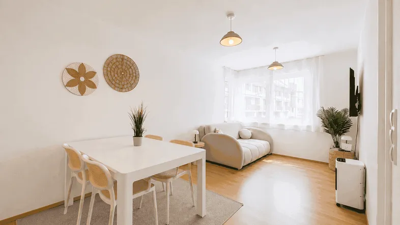 Helles Wohn- und Esszimmer mit Holzboden, modernem Sofa und Esstisch.