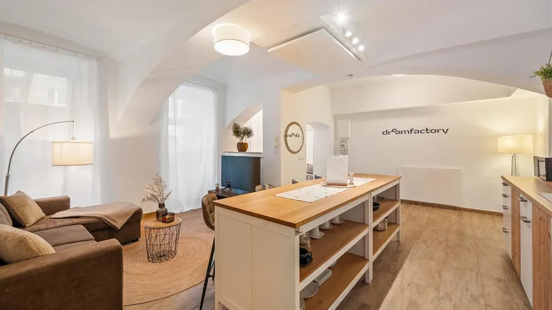 Helles, offenes Wohnzimmer mit Kücheninsel, bequemer Couch und modernen Deckenleuchten.