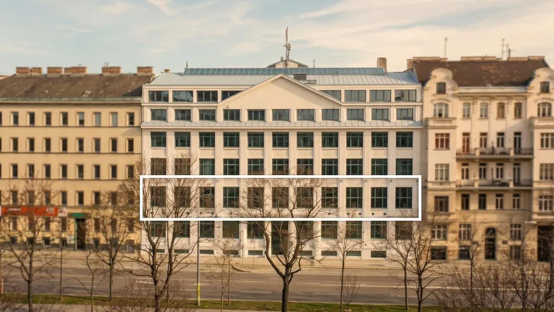 Modernes Bürogebäude mit vielen Fenstern und einer markanten Fassade an einer städtischen Straße.