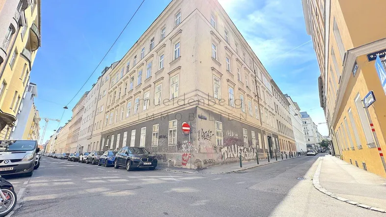 Historisches Eckgebäude in städtischer Umgebung mit Blick auf die Straße und umliegende Gebäude.