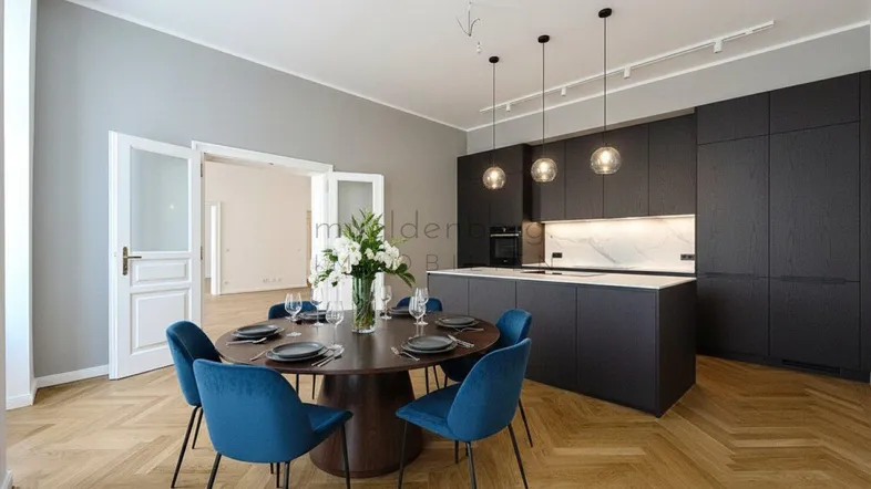 Moderne offene Küche mit dunklen Schränken, Marmorarbeitsplatte und Essbereich mit Fischgrätparkett.