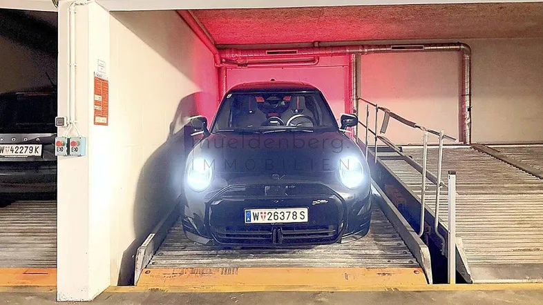 Tiefgarage mit mechanischem Parksystem und einem geparkten Fahrzeug unter roter Beleuchtung.