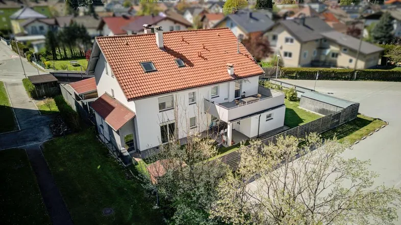 Luftaufnahme eines Einfamilienhauses mit rotem Ziegeldach und umliegender Wohnsiedlung.