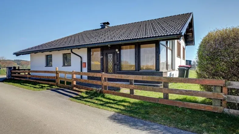 Einfamilienhaus mit Satteldach, großen Fenstern und einem gepflegten Vorgartenbereich.