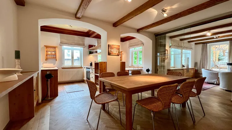 Heller Essbereich mit Holztisch und Stühlen, Parkettboden und Blick in den angrenzenden Wohnbereich.