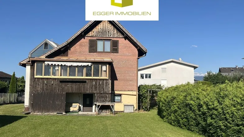 Ansicht des Hauses von hinten mit Gartenbereich und einem verglasten Anbau.