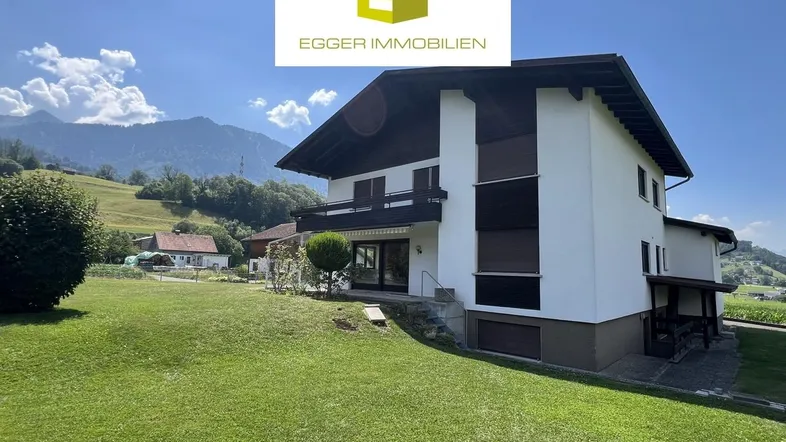 Großzügiges Einfamilienhaus mit Garten und Bergblick, umgeben von grüner Landschaft.