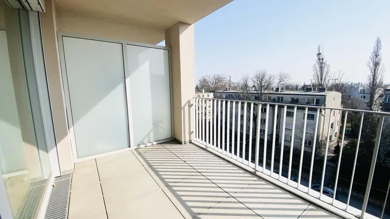 Heller Balkon mit Fliesenboden und Blick auf die umliegenden Gebäude, ideal für sonnige Stunden.