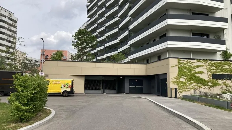 Eingang zur Tiefgarage eines modernen Wohngebäudes mit begrünten Fassadenelementen und Balkonen.