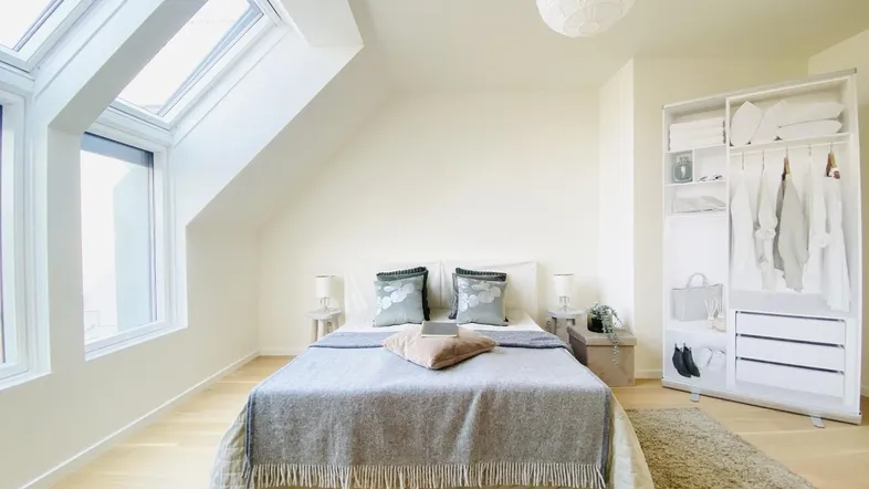 Helles Schlafzimmer mit Dachschrägen, großzügigen Dachfenstern und modernem Interieur.