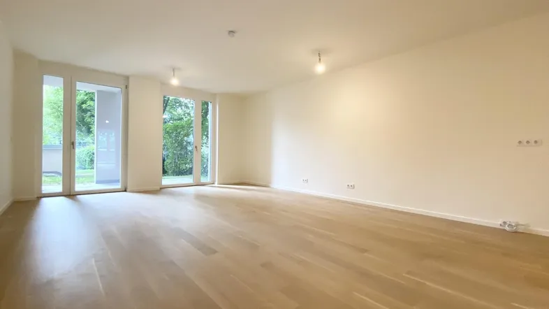 Helles, geräumiges Zimmer mit Parkettboden und großen Glastüren zum Außenbereich.
