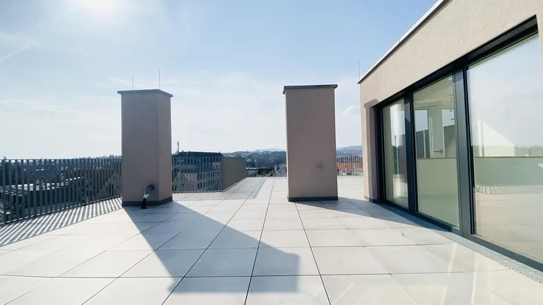 Geräumige Dachterrasse mit hellen Fliesen und weitem Blick über die Stadtlandschaft.