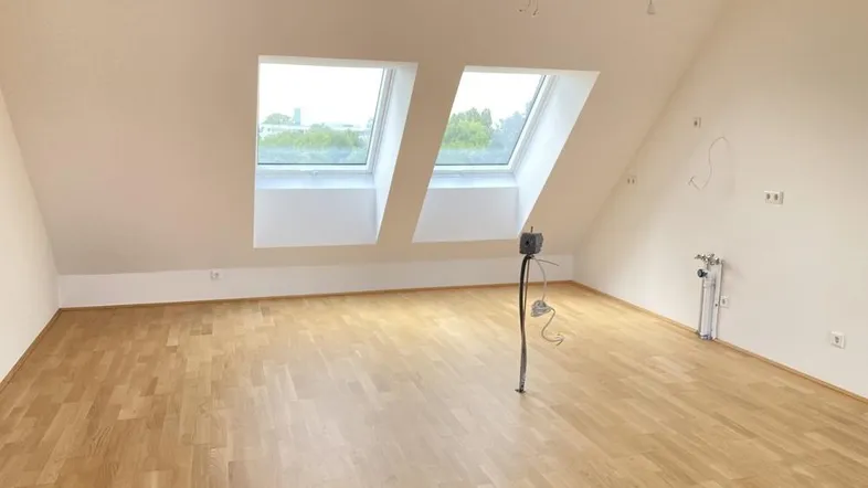 Heller Dachgeschossraum mit Schrägdach, zwei Dachfenstern und Laminatboden, bereit für die individuelle Gestaltung.