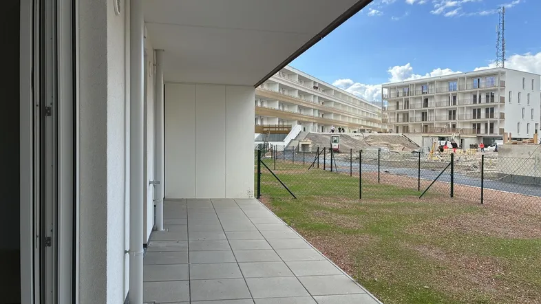 Geflieste Terrasse mit Blick auf die umliegende Neubausiedlung unter blauem Himmel.