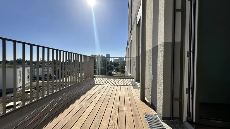 Sonnige Loggia mit Holzboden und Blick auf die Umgebung, ideal zum Entspannen.