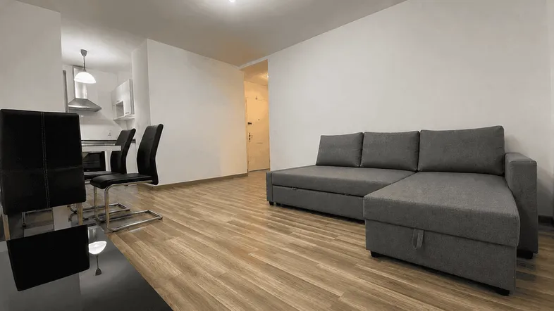Helles, offenes Wohnzimmer mit Sofa, Esstisch und Blick auf die Küche.
