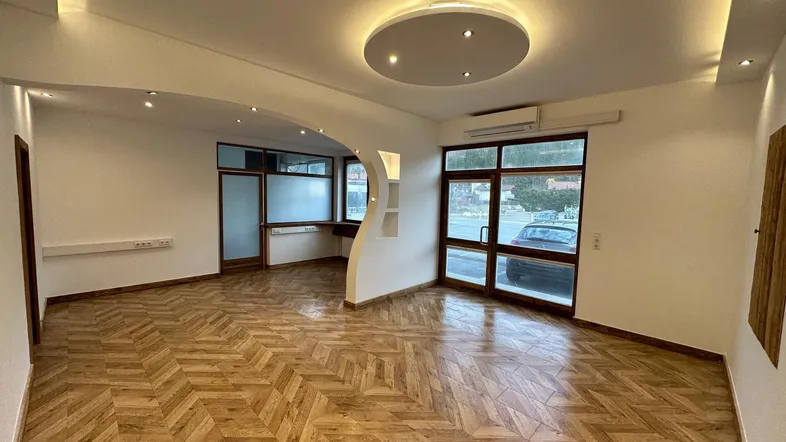 Geräumiger, heller Wohnbereich mit modernem Parkettboden, großen Fenstern und indirekter Deckenbeleuchtung.