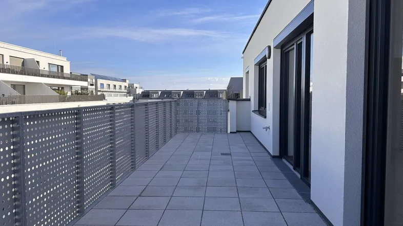 Geräumige Dachterrasse mit modernen Fliesen und perforiertem Metallgeländer, ideal für Entspannung im Freien.