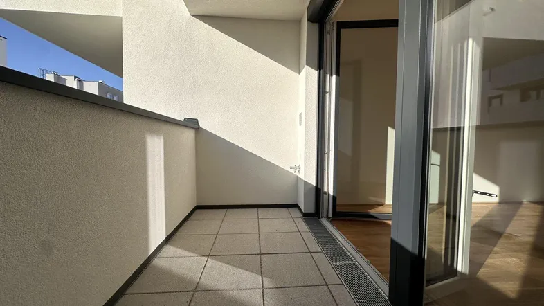 Sonniger Balkon mit Fliesenboden und Blick auf die Umgebung, zugänglich vom Wohnbereich.
