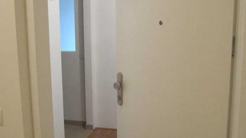 Heller Flur mit Holzboden und offener Tür zu einem weiteren Raum.