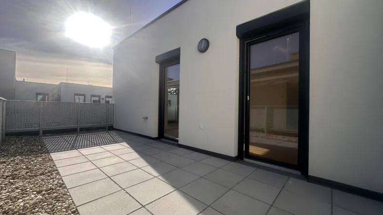 Sonnige Dachterrasse mit Fliesenboden und Kiesbereich, ideal für entspannte Stunden im Freien.