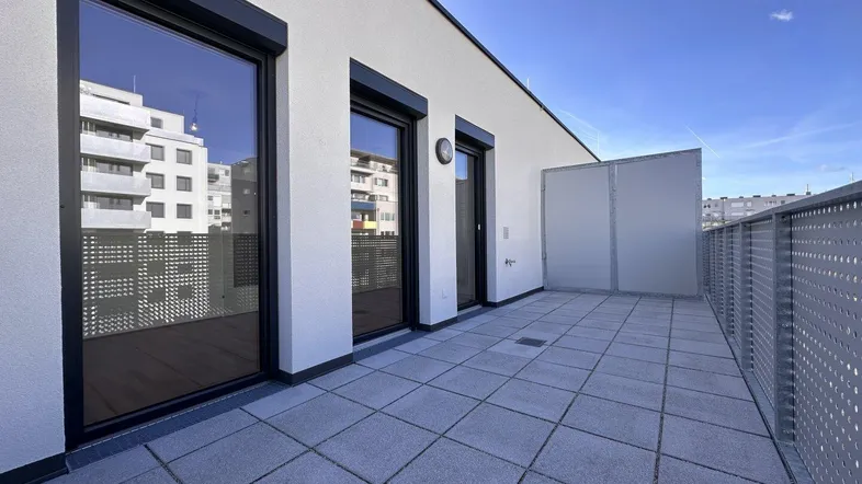 Geräumige Dachterrasse mit modernen Fliesen und Blick auf umliegende Gebäude.