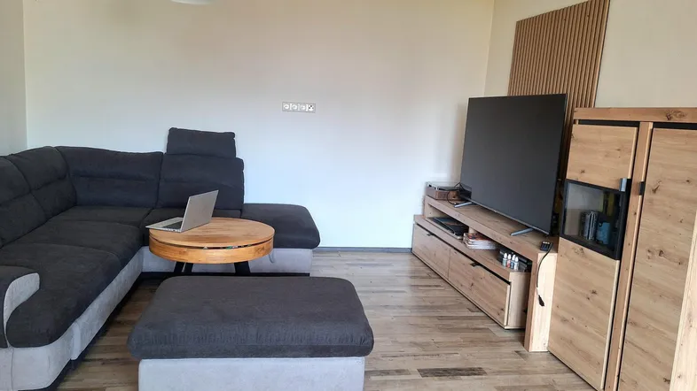 Modernes Wohnzimmer mit gemütlichem Ecksofa, Holzboden und stilvollen Mediamöbeln unter einer Dachschräge.