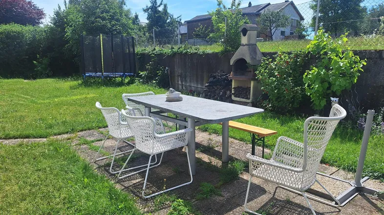 Gepflegter Garten mit Essbereich, Grill und Trampolin, ideal für Familienaktivitäten im Freien.