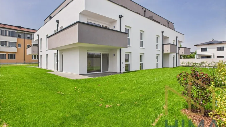 Rückansicht des modernen Wohnkomplexes mit Balkonen und weitläufigen Grünflächen.