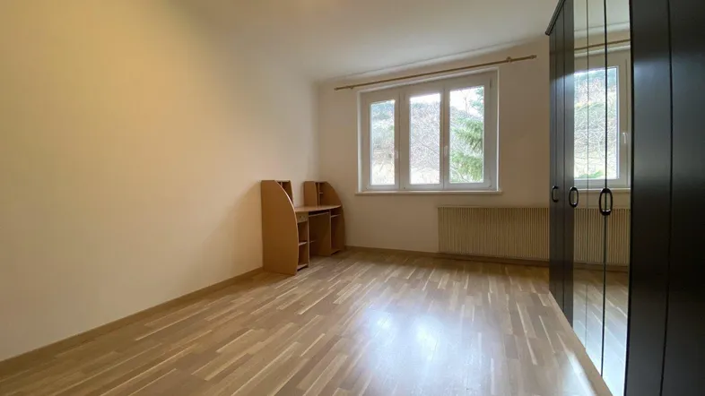 Helles Schlafzimmer mit Parkettboden, großem Spiegelschrank und Blick ins Grüne.