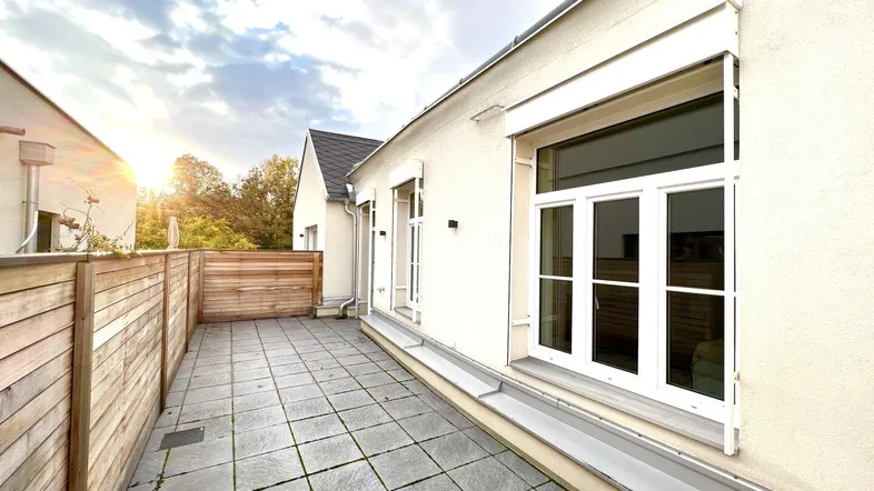 Geräumige Terrasse mit Fliesenboden und Holzabtrennung, ideal für entspannte Stunden im Freien.