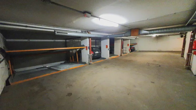 Geräumige Tiefgarage mit modernen Doppelparkern für effizientes Parken und Betonboden.