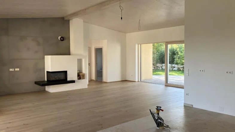 Geräumiges Wohnzimmer mit modernem Kamin, Holzboden und großen Schiebetüren zum Garten.