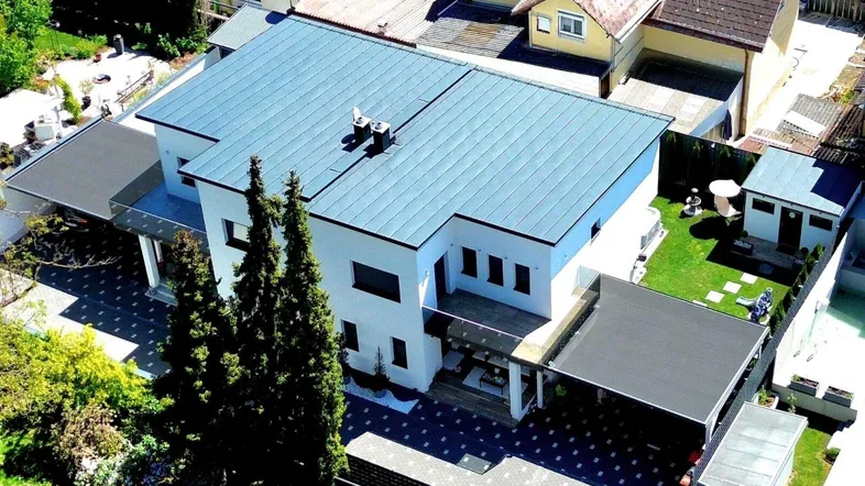 Luftaufnahme eines modernen Einfamilienhauses mit Flachdach und gepflegtem Gartenbereich.