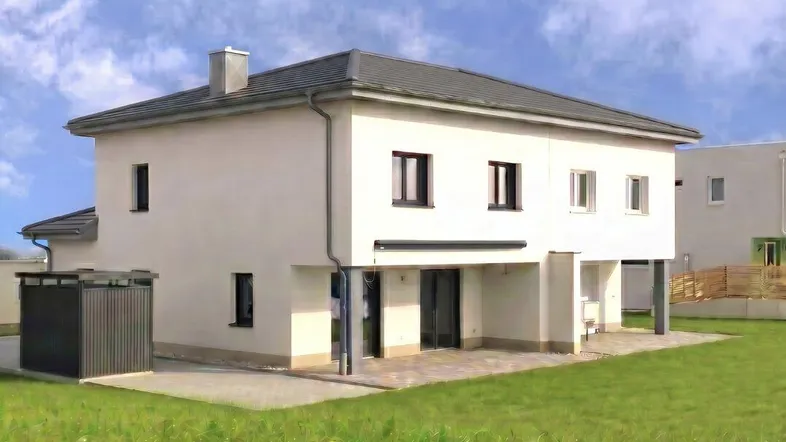 Modernes Einfamilienhaus mit weißer Fassade, Satteldach und großem Gartenbereich.