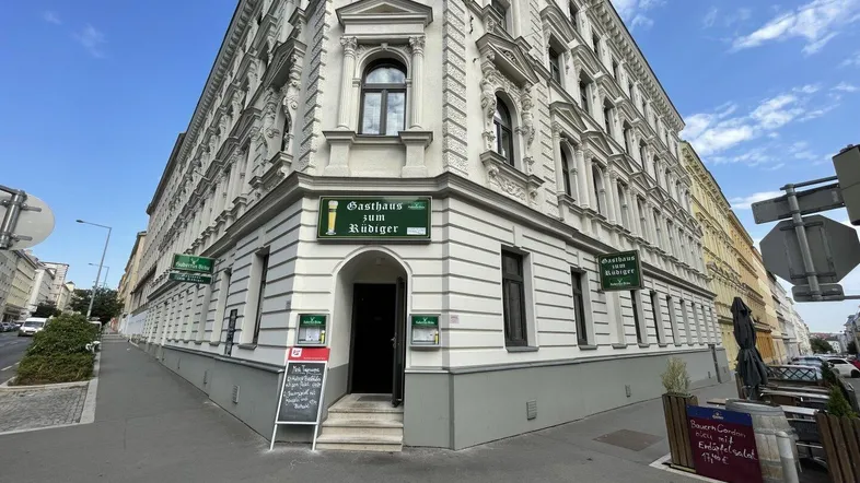 Historisches Eckgebäude mit traditioneller Fassade und dem Eingang zum Gasthaus "Zum Rüdiger" an einer Stadtstraße.