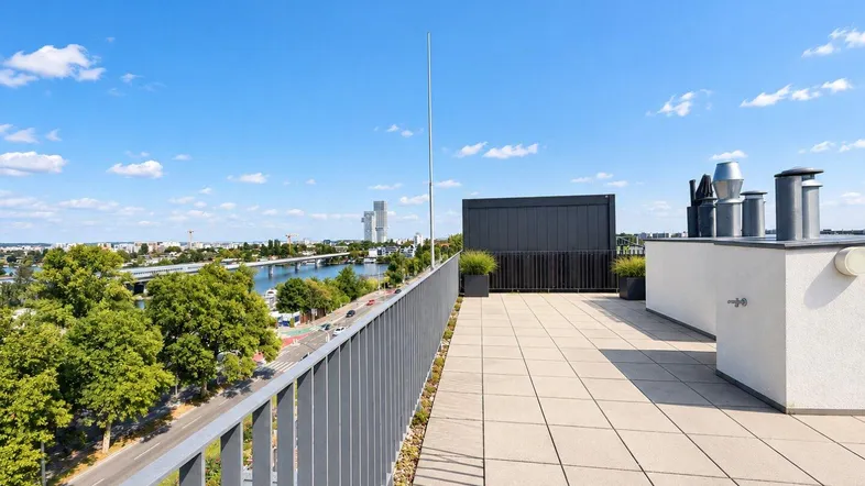Große Dachterrasse mit Fliesenboden und weitem Blick über die Stadt und den Fluss.
