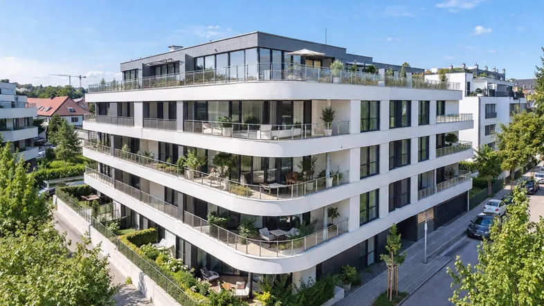 Modernes Mehrfamilienhaus mit mehreren Etagen, Balkonen und Terrassen in einer städtischen Umgebung.