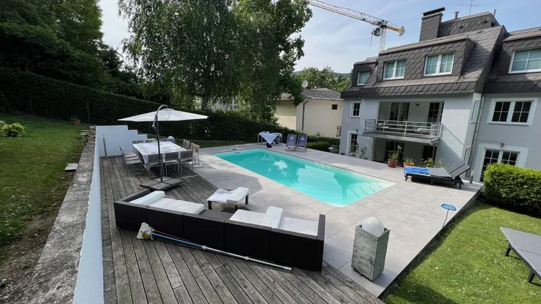 Großzügiger Gartenbereich mit Swimmingpool, Holzterrasse und Essbereich im Freien.
