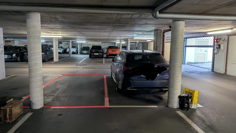 Tiefgarage mit markierten Parkplätzen und Betonstützen, gut beleuchtet.