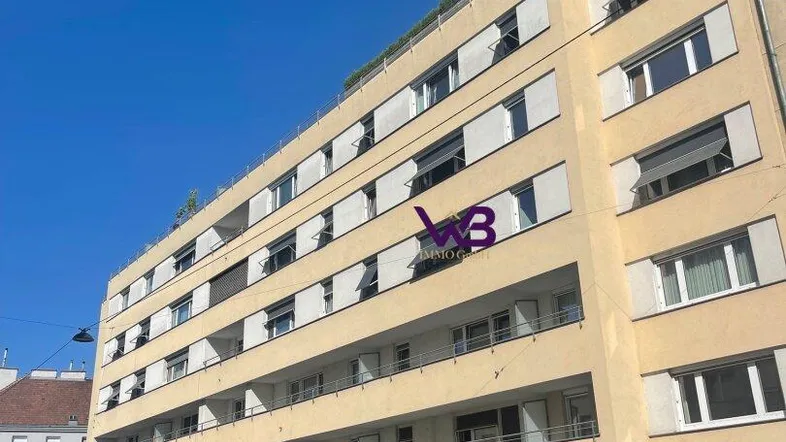 Außenansicht eines modernen Mehrfamilienhauses mit gelber Fassade und Balkonen.
