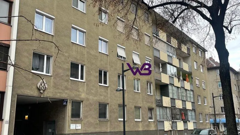 Mehrstöckiges Wohngebäude mit mehreren Fenstern und Balkonen an einer städtischen Straße.
