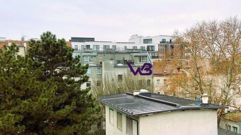 Blick aus dem Fenster auf umliegende Gebäude und Bäume in einer städtischen Umgebung.